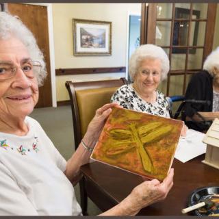 Elderly women enjoying a group art activity, showcasing a painting.