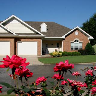 A suburban house with a beautifully landscaped garden featuring blooming red roses.