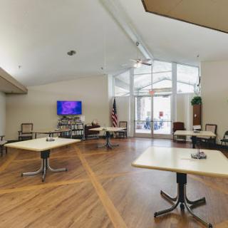 A spacious and modern waiting area with tables and chairs, illuminated by natural light.