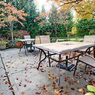 A cozy outdoor patio area with a table and chairs surrounded by autumn foliage.
