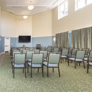 An empty conference room with rows of chairs and a large television in the front.