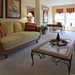 A cozy living room with a sofa, decorative pillows, and a stylish coffee table. Natural light brightens the space through large windows.