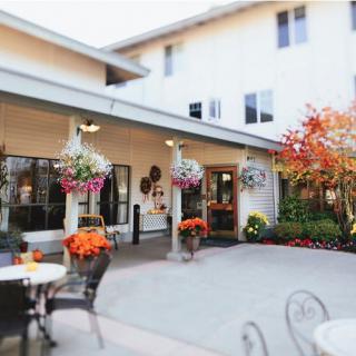A charming courtyard with hanging flower baskets and patio furniture, set against a warm autumn backdrop.