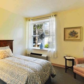 A cozy bedroom with a large window and simple decor.
