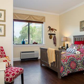 A cozy bedroom with a vibrant bedspread and decorative accents, featuring a window view.