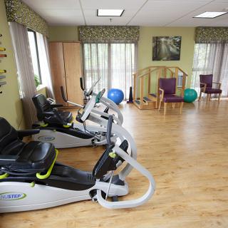 A well-lit indoor fitness space featuring recumbent bikes and wooden flooring, ideal for physical therapy or exercise routines.