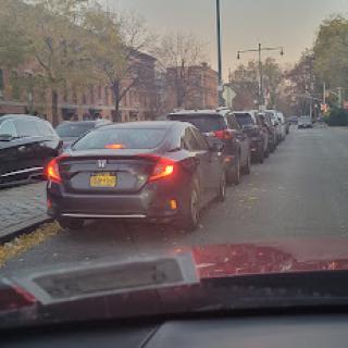 A view of parked cars along a city street during the evening.
