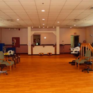 An empty room with a wooden floor and arranged seating, possibly set up for a meeting or event.