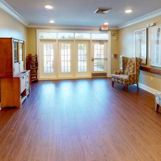 A spacious lobby area with wooden flooring, seating, and large windows allowing natural light.