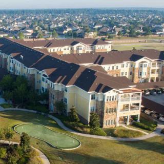Aerial view of a residential apartment complex in a suburban area with landscaped surroundings.