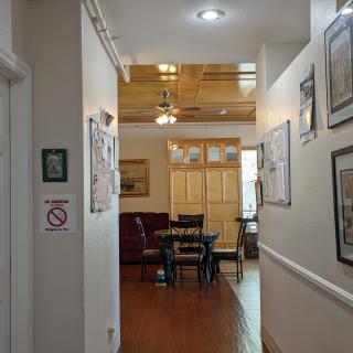 A cozy hallway leading to a dining area with wooden floors and a ceiling fan.