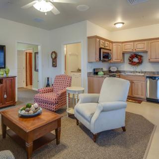 A cozy living room with comfortable armchairs and a coffee table, adjacent to a kitchen area in a modern home.