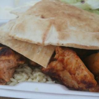 A dish featuring grilled chicken, pita bread, and rice.