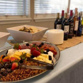A buffet table featuring a platter of assorted fruits and a selection of wine bottles.