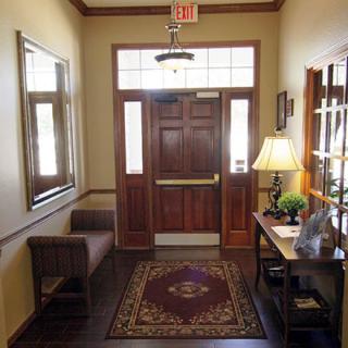 A cozy entrance hallway with a wooden door, mirror, and decorative items.