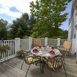 A sunny outdoor patio with a dining set surrounded by greenery.