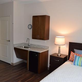 A cozy bedroom with a small kitchenette and modern decor.