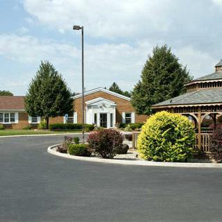 A peaceful suburban setting featuring a road, gazebo, and well-maintained landscaping in front of a brick building.