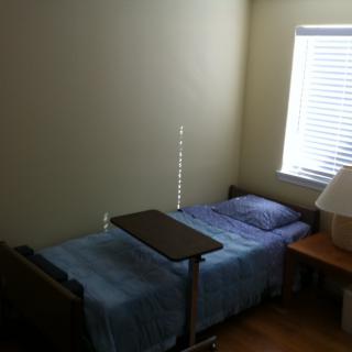 A simple bedroom setup with a single bed, a bedside lamp, and a window.