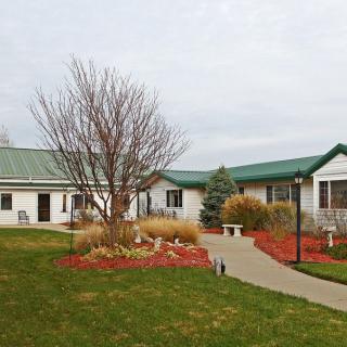 A view of a single-story building with a green roof surrounded by landscaped gardens and a pathway.