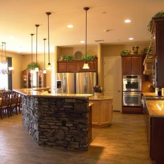 A modern kitchen featuring a stone island, pendant lighting, and stainless steel appliances.