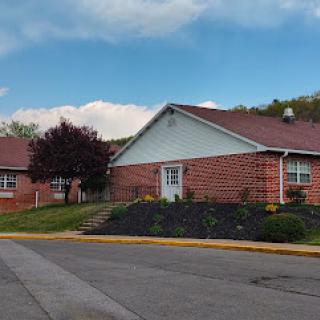 A charming brick residential building with well-maintained landscaping under a partly cloudy sky.