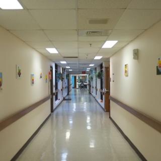 A long hospital hallway with bright lighting and artwork on the walls.