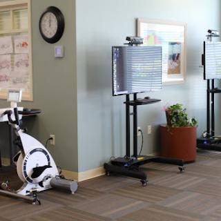 A glimpse into a fitness area featuring a stationary bike and monitor stands, designed for exercise and rehabilitation.