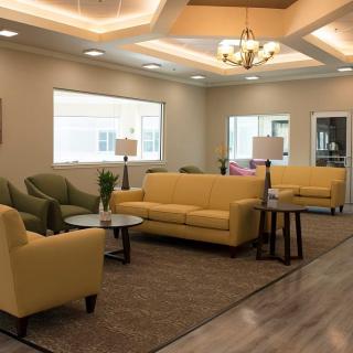 A modern living room with yellow couches, armchairs, and a chandelier.