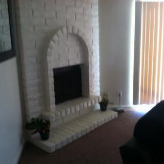 A cozy living room features a white brick fireplace.