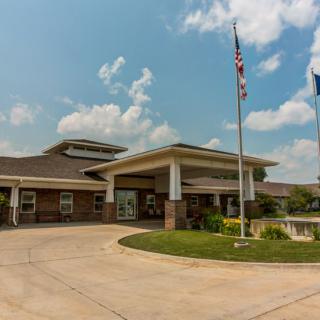 A modern building with a driveway and flags in front under a partly cloudy sky.