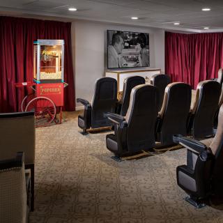 A cozy home theater setup featuring comfortable seating, a popcorn machine, and red curtains.