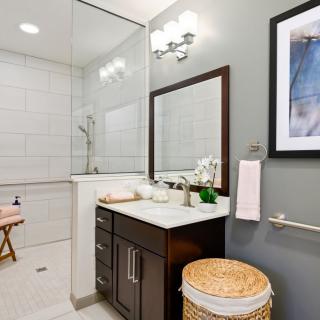 A modern bathroom with a vanity, mirror, and shower area.