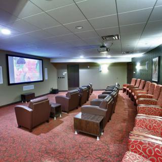 A modern home theater with comfortable seating, a large screen, and a projector.