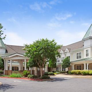 A large residential building with a landscaped entrance and clear blue sky.