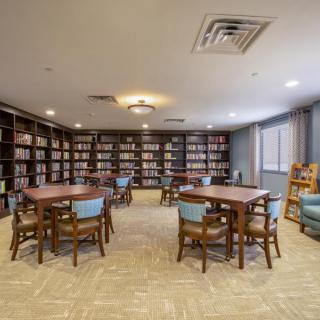 A cozy library room with bookshelves, tables, and chairs perfect for reading.