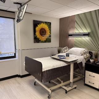 A well-appointed hospital patient room featuring a single bed, modern decor, and a comforting sunflower artwork.