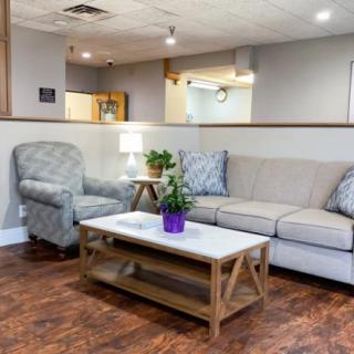 A cozy living room with a beige couch, armchair, and a coffee table featuring an indoor plant.