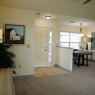 A cozy entrance to a well-lit living space featuring a dining area and artwork on the walls.