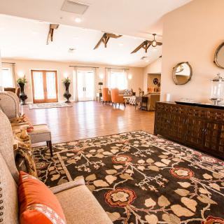 Spacious and elegantly decorated living room featuring modern furniture, a patterned rug, and ample natural light.