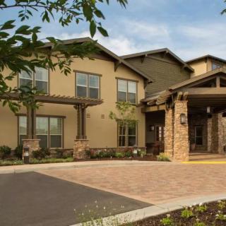 A two-story residential building with landscaped surroundings and a driveway.