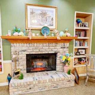 Cozy living room with a brick fireplace surrounded by decorative items and built-in shelves filled with books.