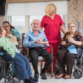 A healthcare worker interacting with elderly individuals in a nursing home setting.