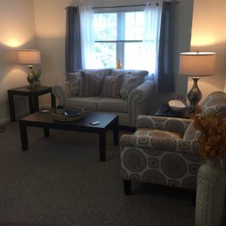 Cozy living room with a sofa, armchair, and warm lighting.