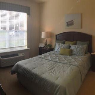 A neatly arranged bedroom with a made bed and bedside lamp.