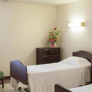 A simple, clean hospital room with two beds and a dresser adorned with flowers.