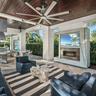 A luxurious outdoor patio featuring comfortable seating, a fireplace, and modern decor.