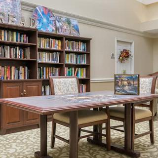 A cozy library nook with a table set for puzzling and bookshelves filled with a variety of books.
