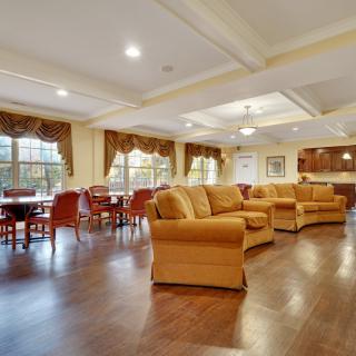Spacious lounge area with comfortable sofas and a dining area, featuring hardwood floors and ample natural light.
