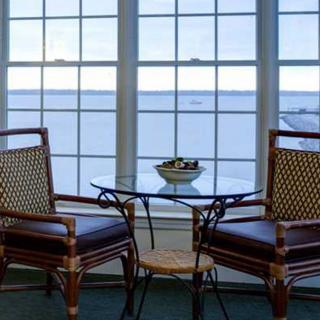A cozy seating area with two chairs and a glass table overlooking a scenic view through large windows.